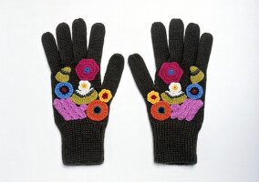 Black gloves embroidered with colourful flowers on white background