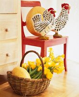 Wooden rooster and hen on chair with daffodils and decorated eggs in basket