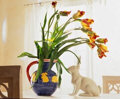 Tulpen in Vase und Dekohase auf Tisch X.