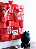 Red wall shelf with various compartments for stationery items