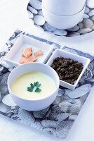 Selleriesuppe in einer Schale, dazu Forellenfilet und Pumpernickelwürfel