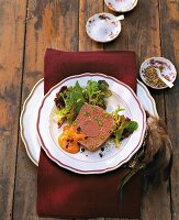 Wild boar terrine wrapped with rosehip sauce and lettuce on plate