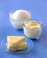 Mozzarella cheese and processed cheese in glass bowl and plate on blue background