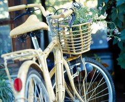Fahrrad mit bambusverkleidetem Rahmen, Korb mit Blumen am Lenkrad
