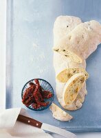 Baked ciabatta with olives and dried tomatoes on serving dish
