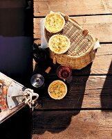 Quiche on picnic basket and wine glasses and bottle on jetty