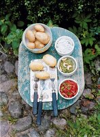 Boiled potatoes on table with various dips and forks on plate, overhead view