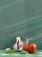 Tomato, garlic and basil leaves against green background