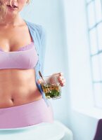 Woman wearing lingerie holding glass with mint and spoon