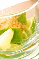 Brauner Zucker im Glas mit Limonenstücken für Caipirinha