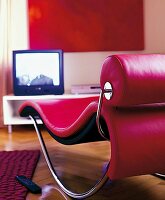 Blick auf eine elegante rote RelaxLiege und Fernseher davor, nah