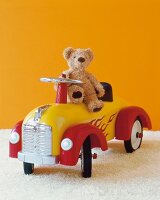 Teddy bear on red and yellow toy car