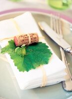 Close-up of napkin decorated with wine corks and grape leaf