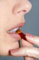 Close-up of woman holding a pill on lip