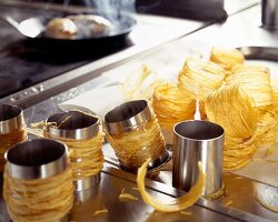 Fried potatoes wrapped around metal rings for potato basket