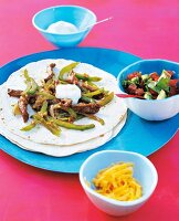 Fajitas with beef and bowl of salsa on serving plate