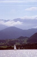 View of mountains with sail boat sailing on Traunsee lake in Salzkammergut