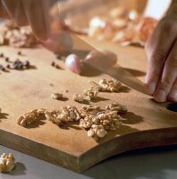 Close-up of walnuts being chopped by knife on chopping board