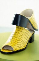 Close-up of bright yellow sabot sandals with crocodile pattern and block heel