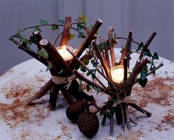 Tea light candle on bundles of branches tied with raffia on rustic table