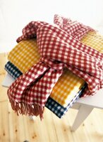 Three colourful small check pattern blankets made of lambs wool on table