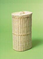 Light brown wicker laundry basket on green background