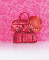 Two red purse and hat against pink background