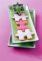 Kekse und Ausstechform in Puzzleform liegen auf grünen Keramikschalen