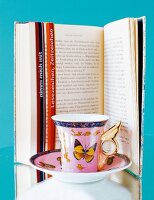 Espressotasse mit SchmetterlingDekor, dahinter Buch mit Lesezeichen