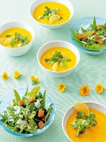 Carrots and lime soup with avocado, herbs and mangetout salad in bowl