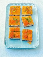Salmon slices with cream cheese, salmon caviar and herbs on serving plate