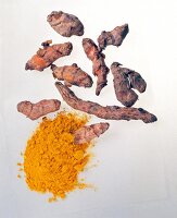 Fresh turmeric roots and powder on white background