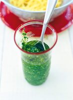 Close up von Glas mit grünem Pesto mit Löffel darin