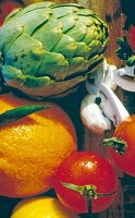 Close-up of various foods like orange, artichoke, mushrooms and tomato