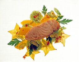 Close-up of fried salmon with star fruit, kiwi, oranges, spring and onions