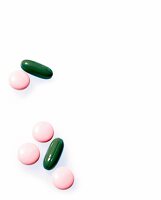 grüne, ovale Pillen und rosane, runde Pillen