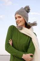 Beautiful woman wearing green sweater, jeans and scarf standing with arms crossed, smiling