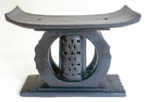 Close-up of ashanti stool made of black patina with wooden carving on white background