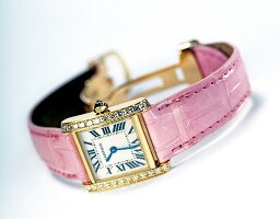 Close-up of pink wristwatch studded with diamonds on white background