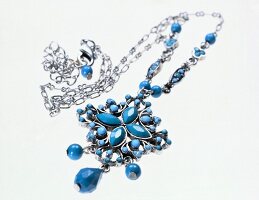 Close-up of necklace with turquoise stones on white background