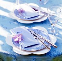 Blue and white table setting with menu cards, cutlery and wine glass