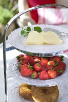 Dreistöckiges Tablett mit Herzen aus Butter, Erdbeeren und Donuts. x