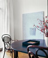 Tisch schwarz, rund + Thonet-Stuhl im hellen Wohnzimmer in Weiß