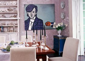 Esszimmer: gedeckter Tisch, silberne Kerzenhalter und Pop-Art-Gemälde