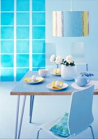 Dining area with blue table, chair, flowers in vase and striped lamp