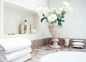 Ein Strauß Blumen in eleganter Vase auf Badewannenrand