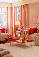 Wohnzimmer mit hellen Möbeln, Katze liegt auf dem Sofa, rote Kissen