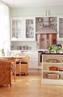 Modular kitchen with white installation, wooden table and wicker chairs