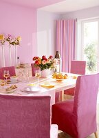 Laid out table with pink chairs and flower vases against pink wall