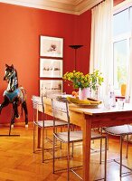 Dining room with red wall, wooden table and carousel horse